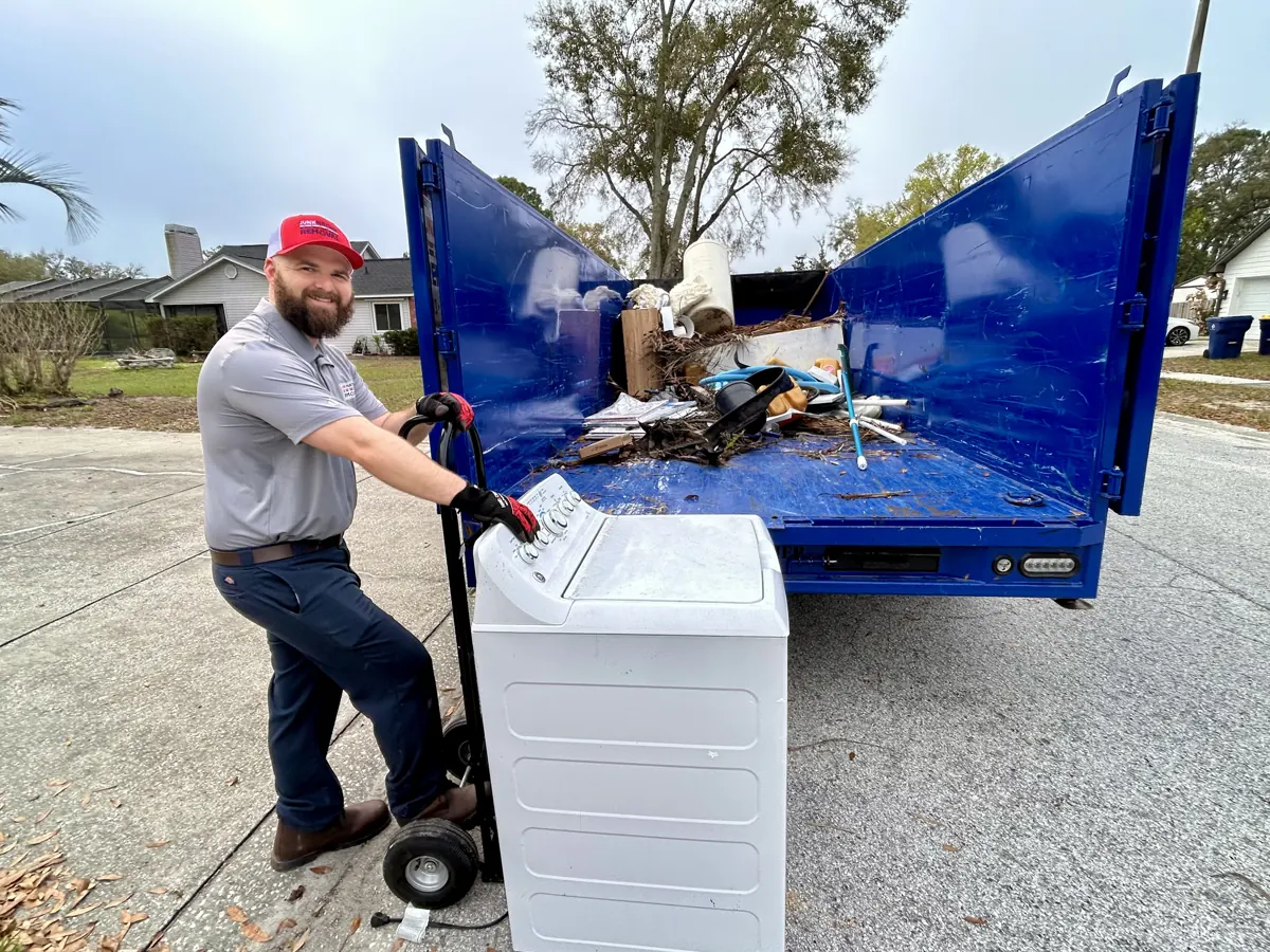 Junk Nation Removal crew loading appliances onto a dolly at the branded truck in the Tampa Bay area